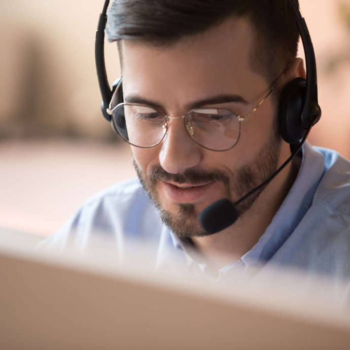 Man med headset sitter och pratar framför en dator.